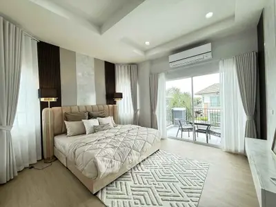 Luxurious bedroom with elegant decor and balcony access, featuring modern furnishings and ample natural light.