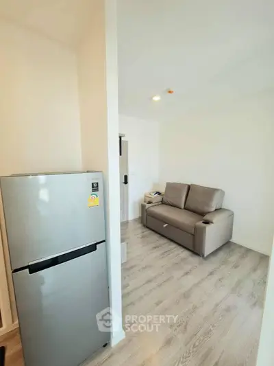 Modern living room with sleek fridge and cozy sofa, perfect for urban living.