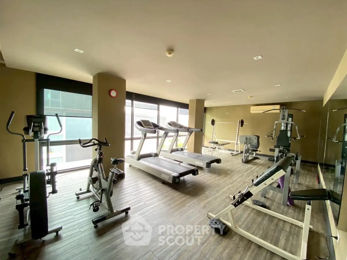 Modern gym with state-of-the-art fitness equipment and large windows for natural light.