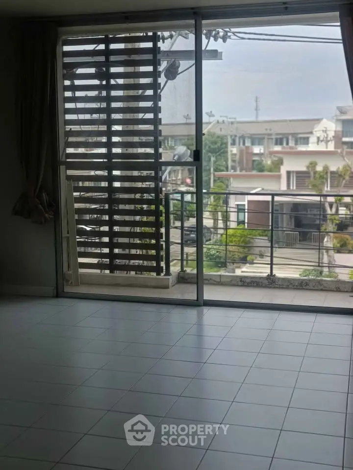Spacious apartment with large windows and balcony offering a serene neighborhood view.