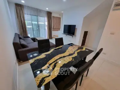 Modern living room with stylish dining area and large sofa, featuring a sleek TV setup.