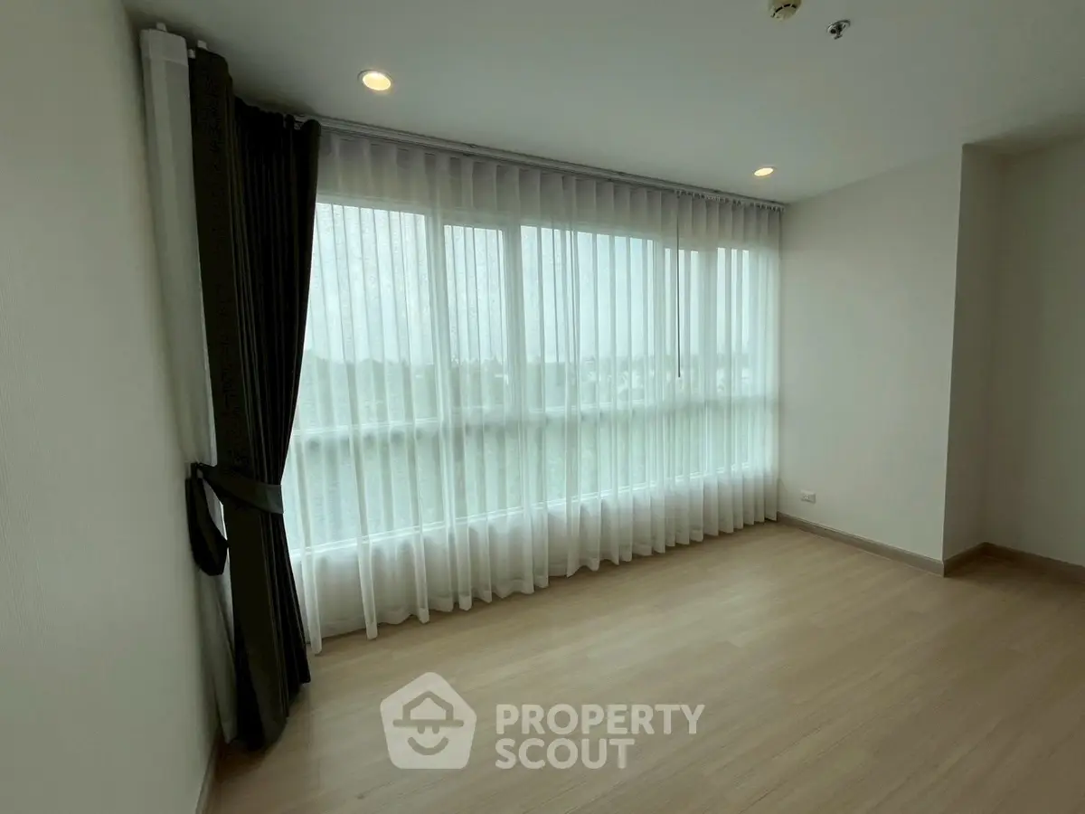 Spacious empty room with large windows and elegant curtains