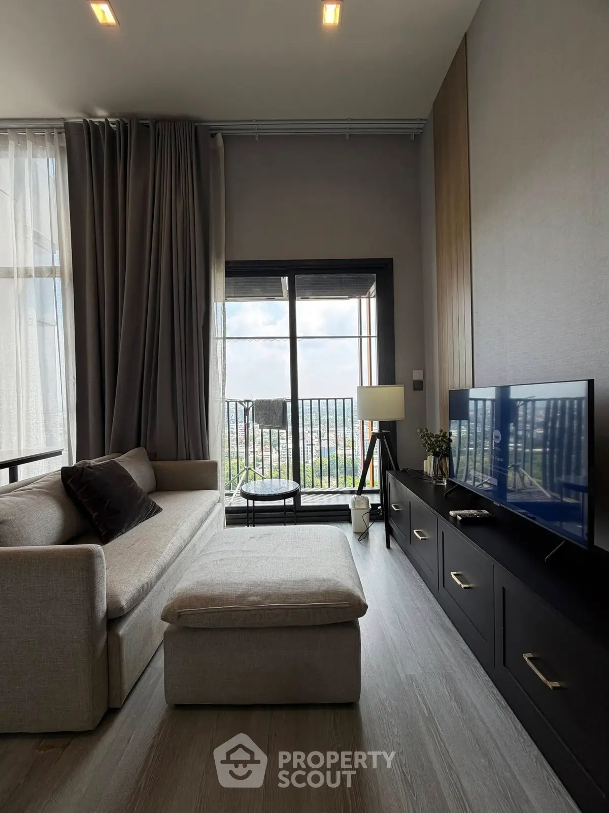 Modern living room with large window and city view, featuring sleek furniture and stylish decor.