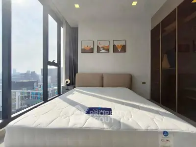 Modern bedroom with large windows and city view, featuring a stylish bed and contemporary decor.