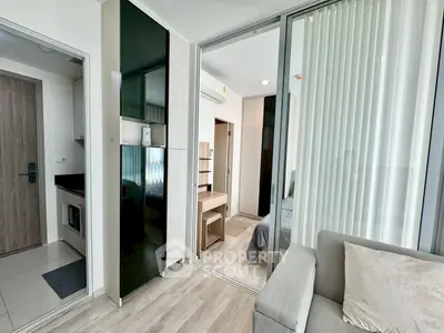 Modern apartment interior with sleek design, featuring a cozy living area and stylish bedroom separated by glass doors.
