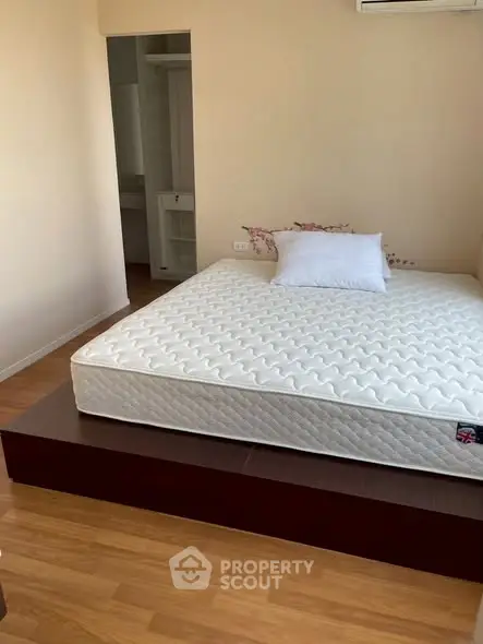 Spacious bedroom with wooden flooring and a comfortable mattress on a raised platform, ideal for relaxation.