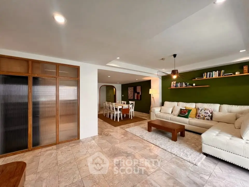 Spacious living room with modern decor and dining area, featuring elegant lighting and stylish furniture.