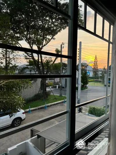 Charming neighborhood view from window with sunset backdrop