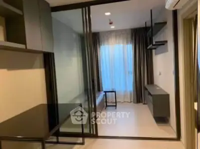 Modern apartment interior with glass partition and sleek furniture design.