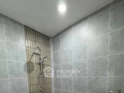 Modern bathroom with sleek gray tiles and a stylish shower fixture.