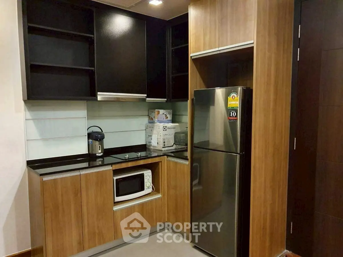 Modern kitchen with sleek cabinets, stainless steel fridge, and built-in microwave.