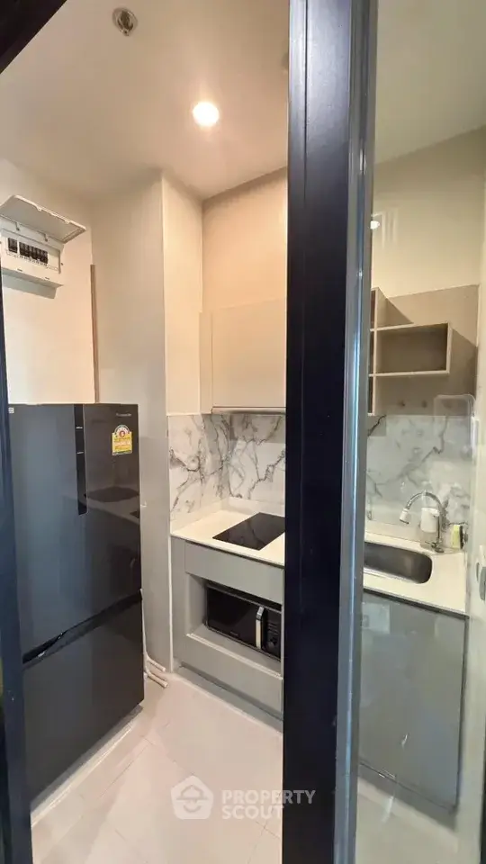 Modern compact kitchen with sleek appliances and marble backsplash