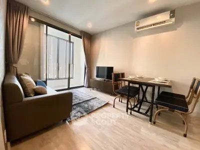 Modern living room with balcony access, featuring sleek furniture and air conditioning.