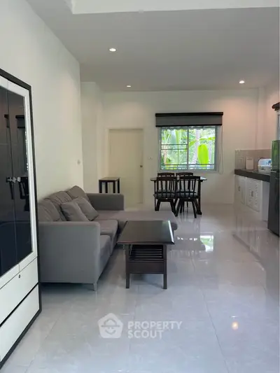 Spacious living room with modern furniture and open kitchen layout, perfect for comfortable living.