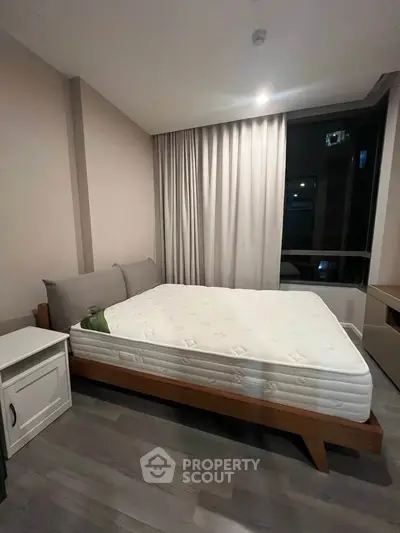 Modern bedroom with sleek design and large window, featuring a comfortable bed and stylish decor.