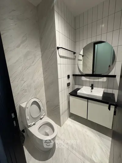 Modern bathroom with sleek design featuring a round mirror and elegant fixtures.