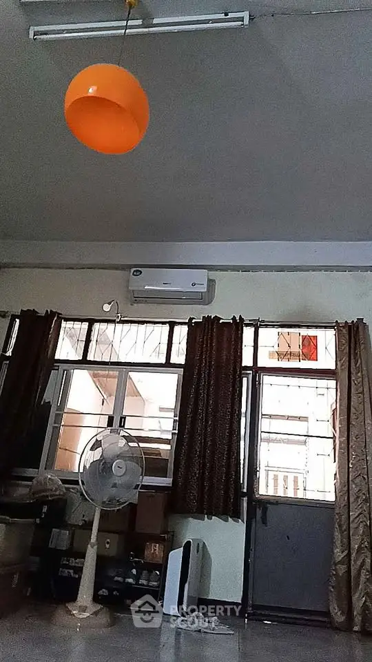 Spacious living room with large windows and modern air conditioning unit.