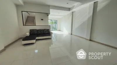 Spacious living room with gleaming tiled floors, modern staircase, and abundant natural light, perfect for elegant entertaining and comfortable living.