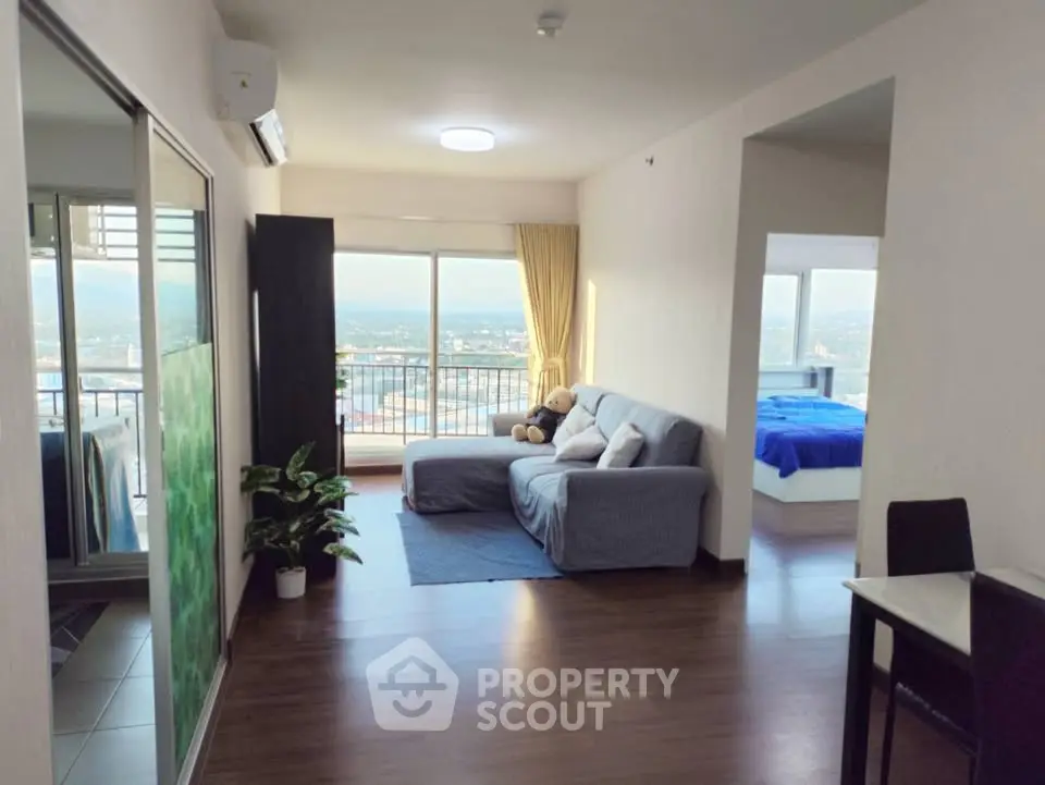 Spacious open-plan living room with balcony and scenic view, featuring cozy seating and modern decor.