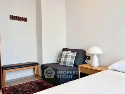 Cozy bedroom corner with modern chair, stylish lamp, and elegant decor
