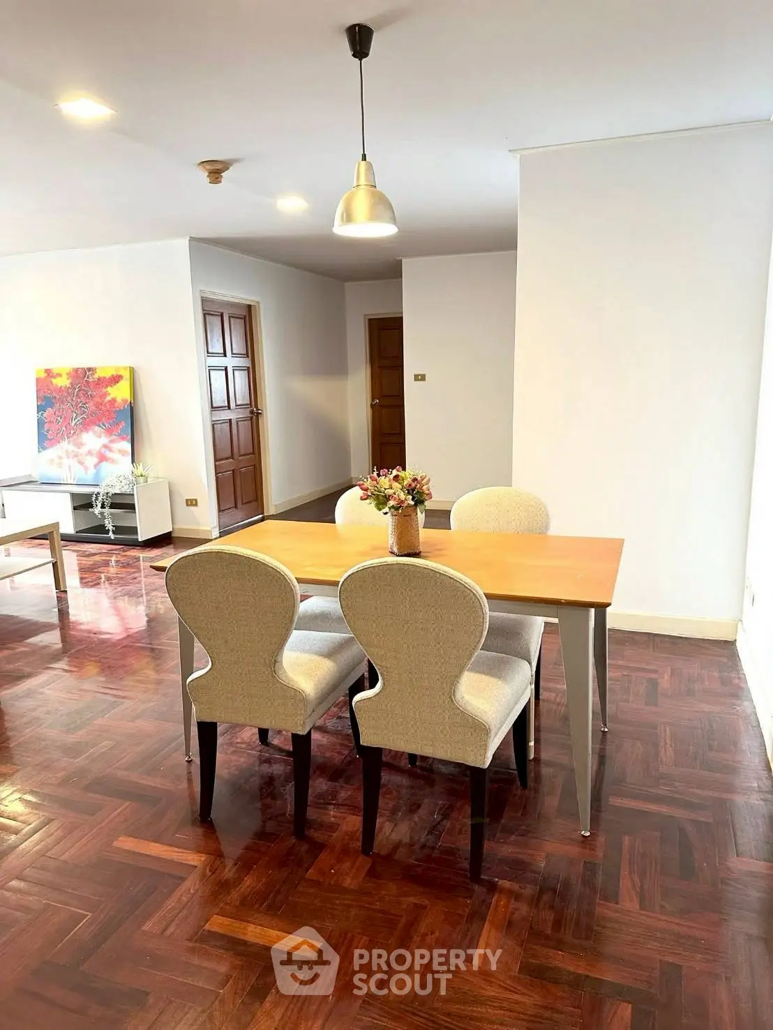 Elegant dining area with wooden flooring and modern decor in a spacious apartment.