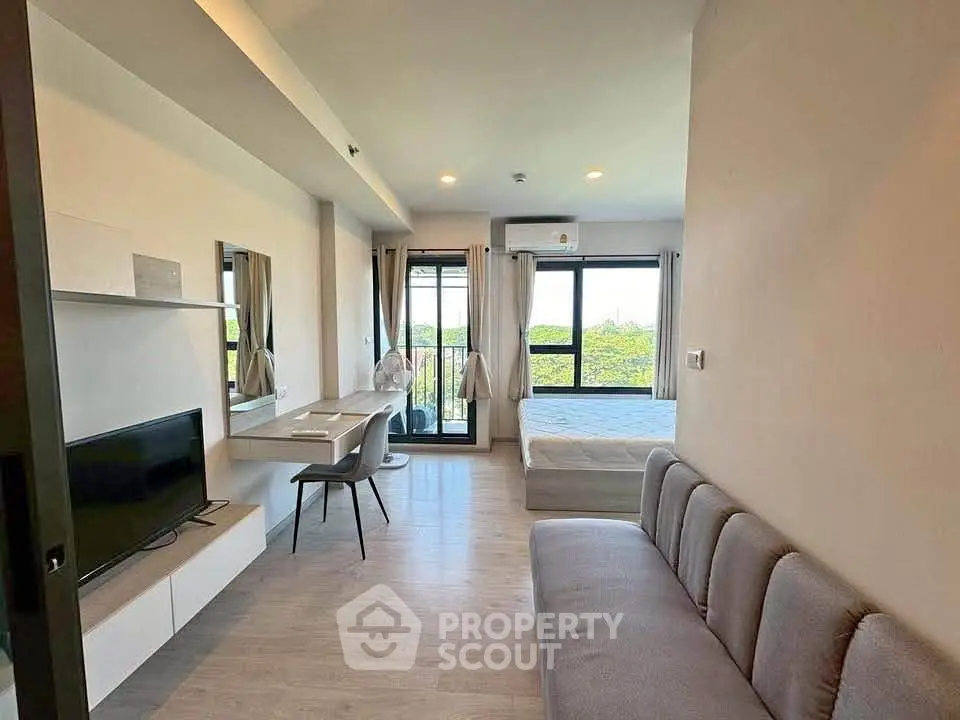 Modern studio apartment with open layout, featuring a cozy living area, workspace, and large windows with scenic views.