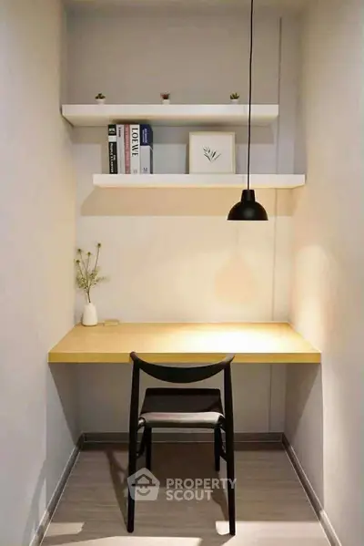 Minimalist study nook with wooden desk, chair, and shelves in modern apartment.