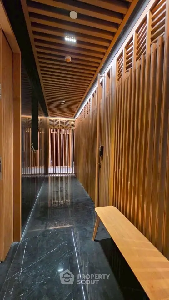 Luxurious modern building corridor with sleek wooden paneling and polished black marble flooring.