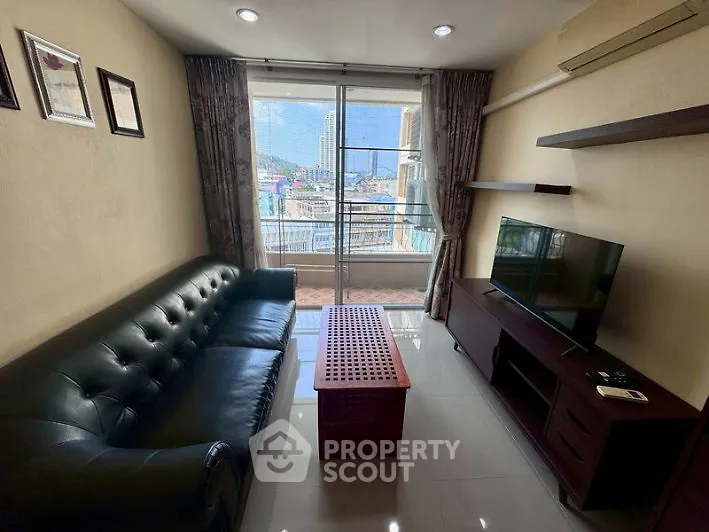 Cozy living room with leather sofa, TV, and balcony view in modern apartment.