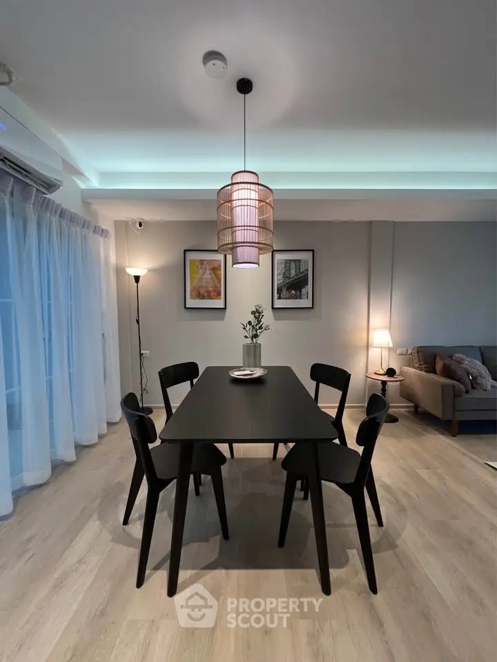 Modern dining area with stylish black table and chairs, ambient lighting, and cozy decor.
