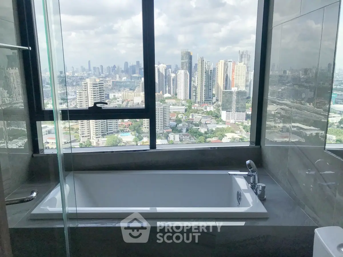 Luxurious bathroom with stunning city view from high-rise apartment window.