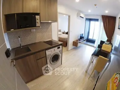 Modern apartment interior with kitchen and living area, featuring a washing machine and open layout.