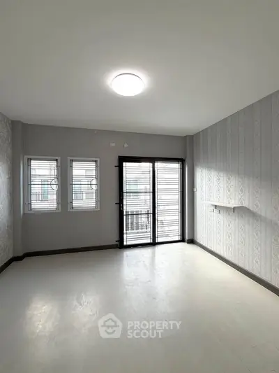 Spacious empty room with large windows and balcony access, perfect for customization.