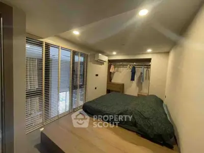 Cozy bedroom with modern design and ample natural light from large windows.
