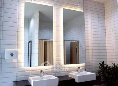 Modern bathroom with dual sinks and illuminated mirrors in stylish real estate property.