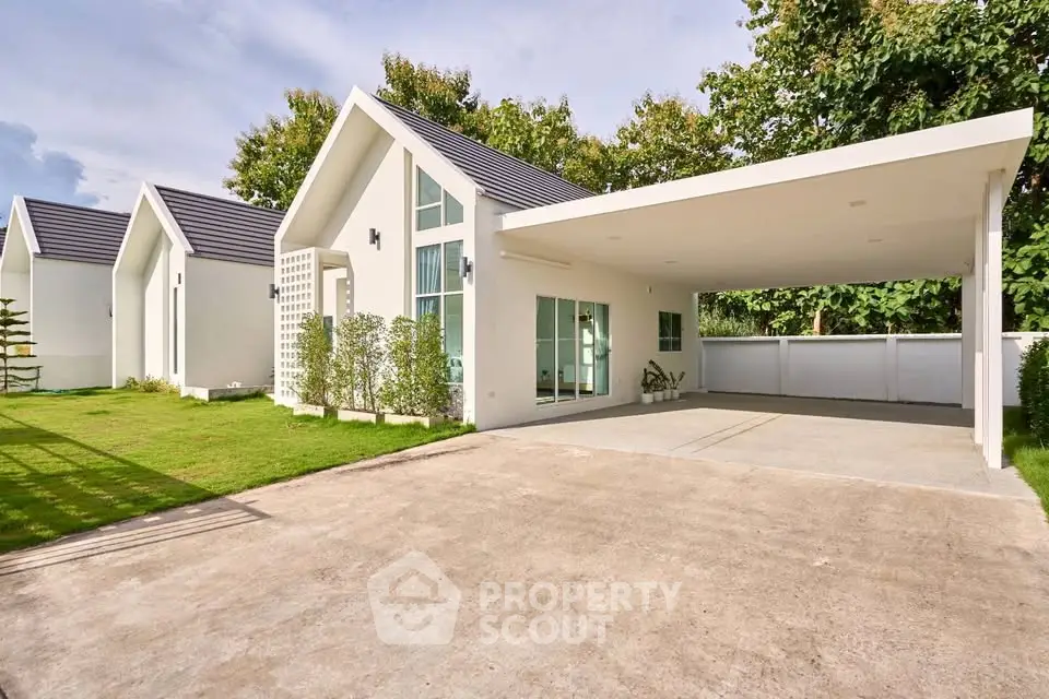 Modern white house with carport and lush green surroundings