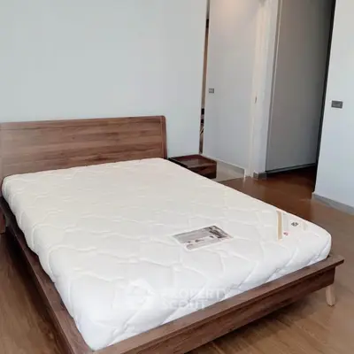Spacious bedroom with modern wooden bed frame and cozy mattress in a stylish apartment.