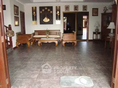 Spacious living room with elegant wooden furniture and decorative art pieces, offering a warm and inviting atmosphere.