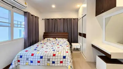 Modern bedroom with stylish decor and ample natural light, featuring a cozy bed and built-in wardrobe.