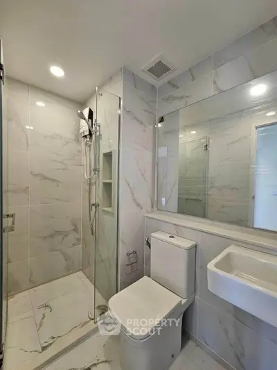 Modern bathroom with sleek design, featuring glass shower and elegant marble tiles.