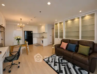 Spacious modern living room with open kitchen, elegant chandelier, and cozy seating area.