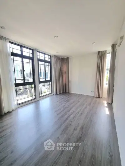 Spacious empty living room with large windows and elegant curtains