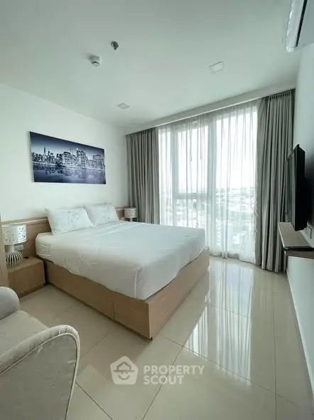 Modern bedroom with large window and city view, featuring a cozy bed and stylish decor.