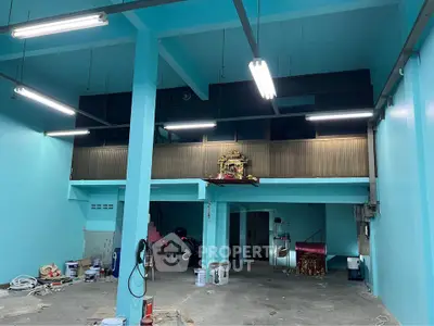 Spacious industrial-style interior with high ceilings and mezzanine, ideal for creative workspace or studio.