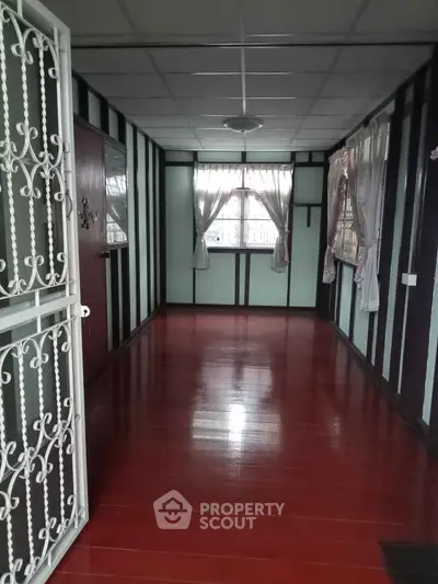 Charming hallway with polished wooden floors and decorative window curtains