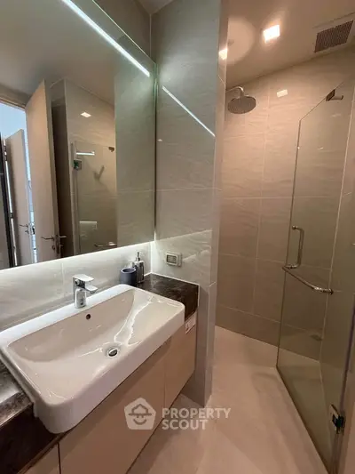 Modern bathroom with sleek design, featuring a spacious shower and elegant sink area.