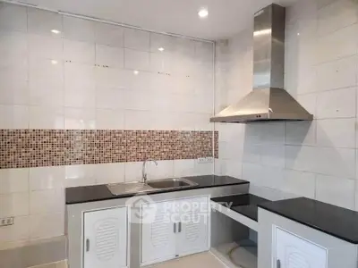 Modern kitchen with sleek black countertops and stainless steel range hood