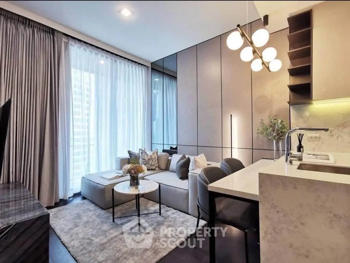 Modern living room with elegant decor and open kitchen layout, featuring stylish lighting and cozy seating.