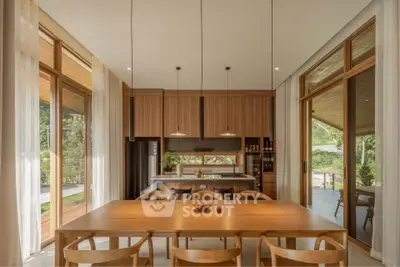 Spacious modern kitchen with wooden cabinetry and large dining table, featuring open layout and natural light.