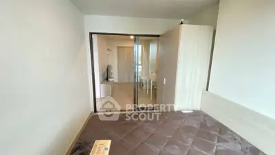 Modern bedroom with sliding glass doors leading to a bright living area, featuring sleek furniture and neutral tones.